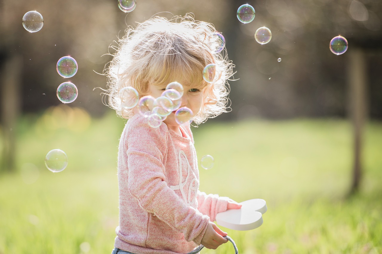 little girl outside with bubbles floating in the air