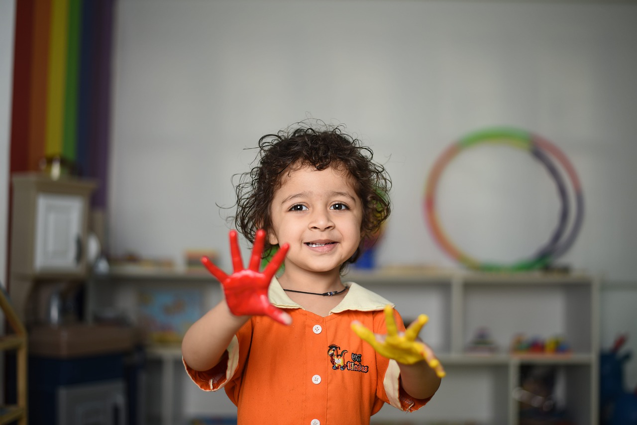 curly headed toddler with paint all over her hands