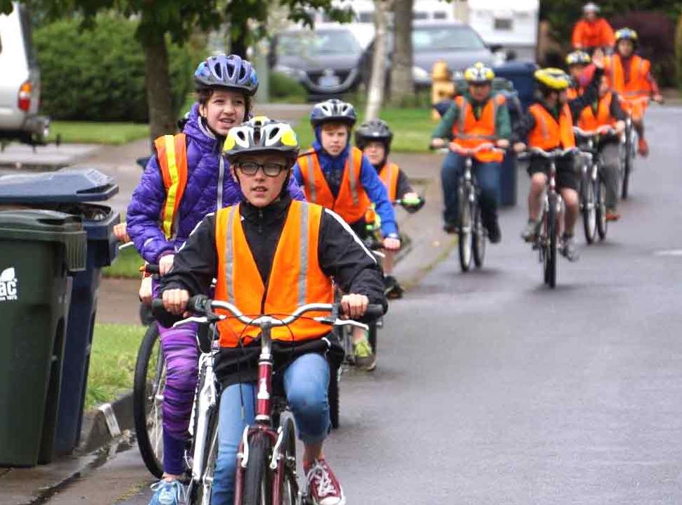 a line of children in safety vests riding bikes