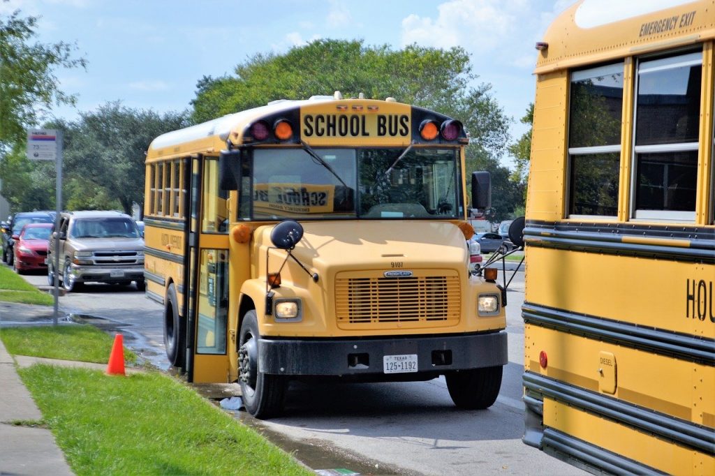2 school buses parked at the curb of a school