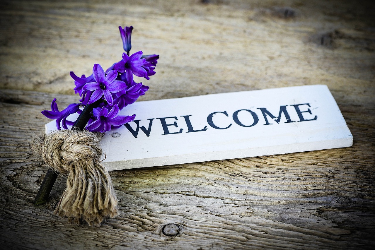 wooden welcome sign with a hyacinth lying next to it