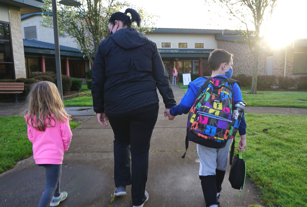 Woman walking two children to school