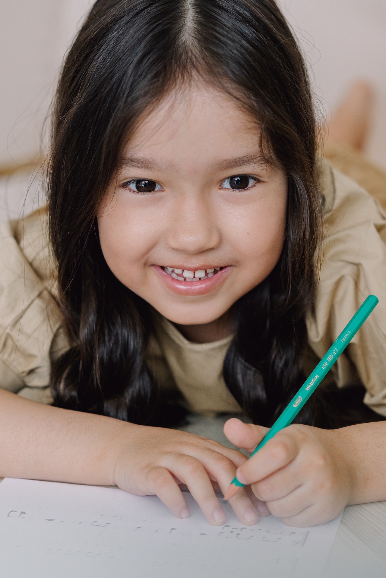 young girl smiling and holding green pen