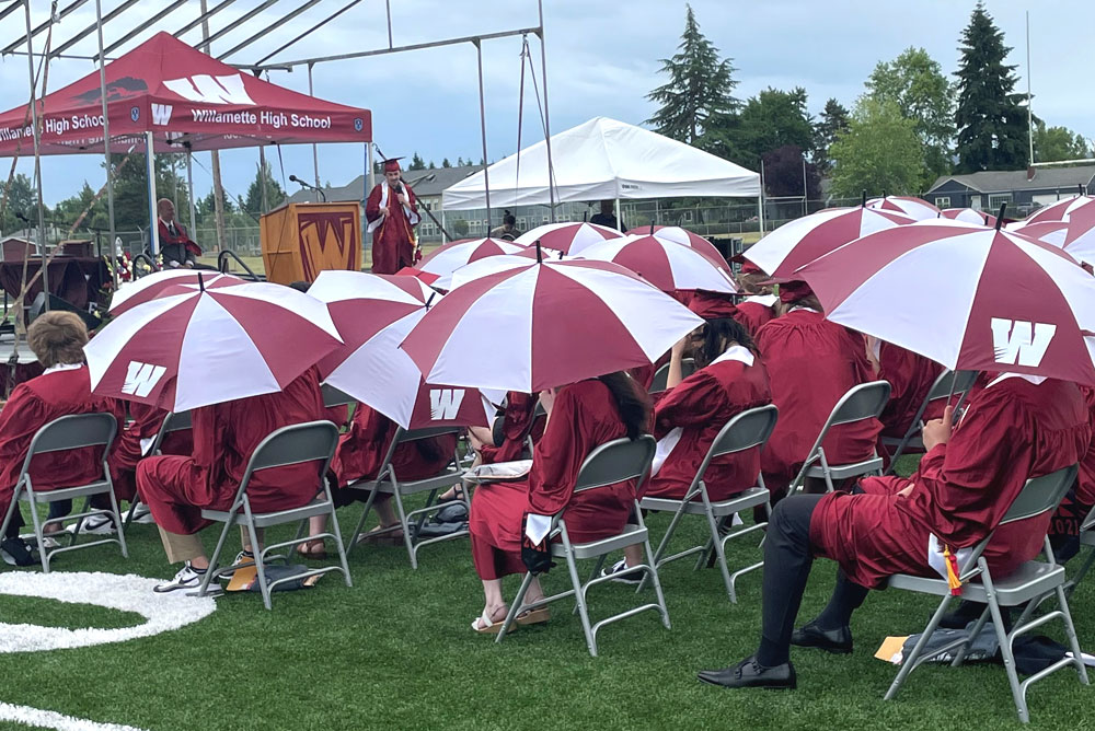 students sitting under umbrellas during graduation