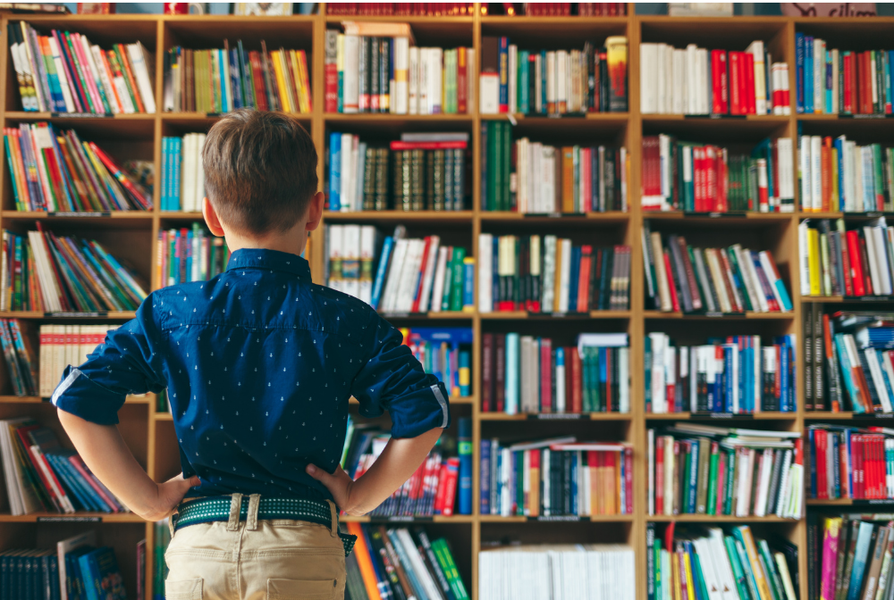 child with his back to the camera looking at shelves of books