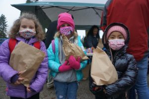 3 students bundled up against the cold holding paper bags