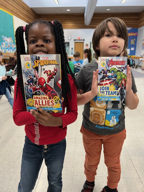 two students hold up books at a school