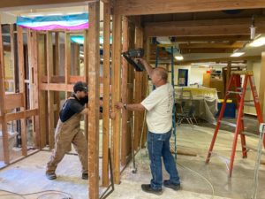 Two men nailing walls in place to build a classroom