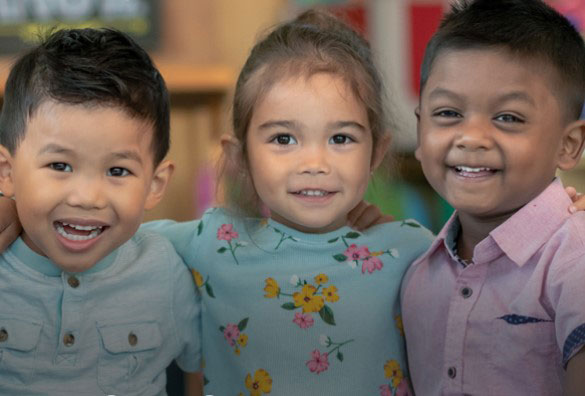 Three young children smiling at the camera